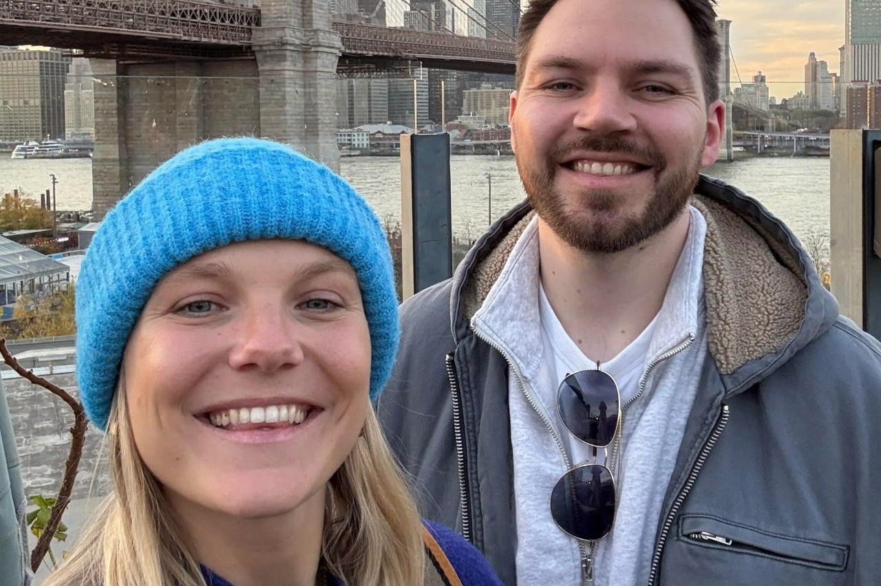 Couple posing in front of the Brooklyn Bridge in New York City.