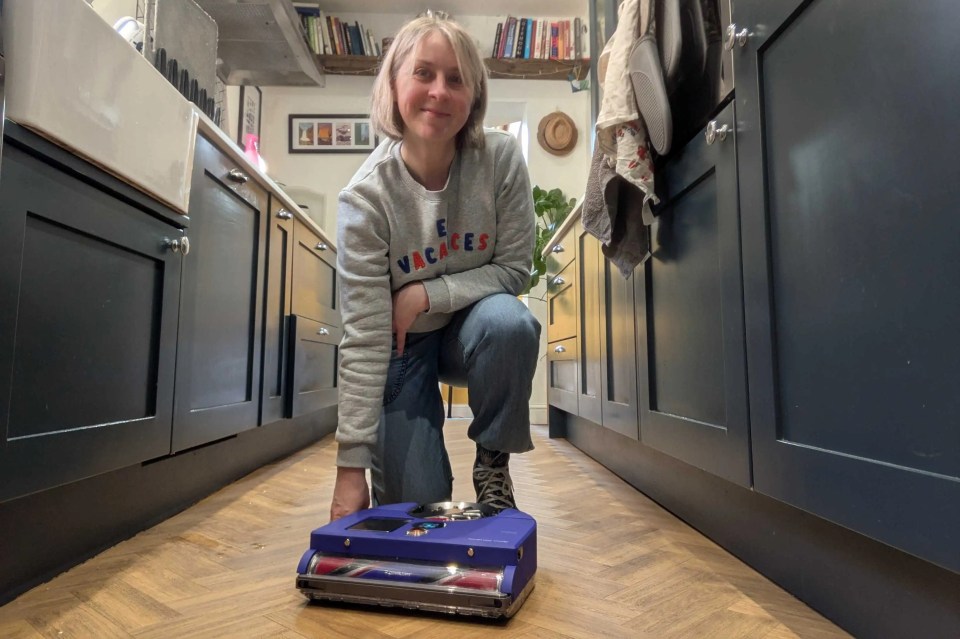 Senior Feature Writer Alex Lloyd kneels next to the Dyson 360 Vis Nav