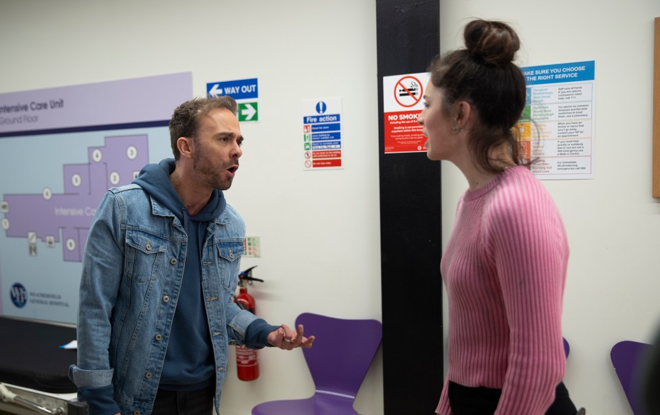 A man and a woman arguing in a hospital hallway.