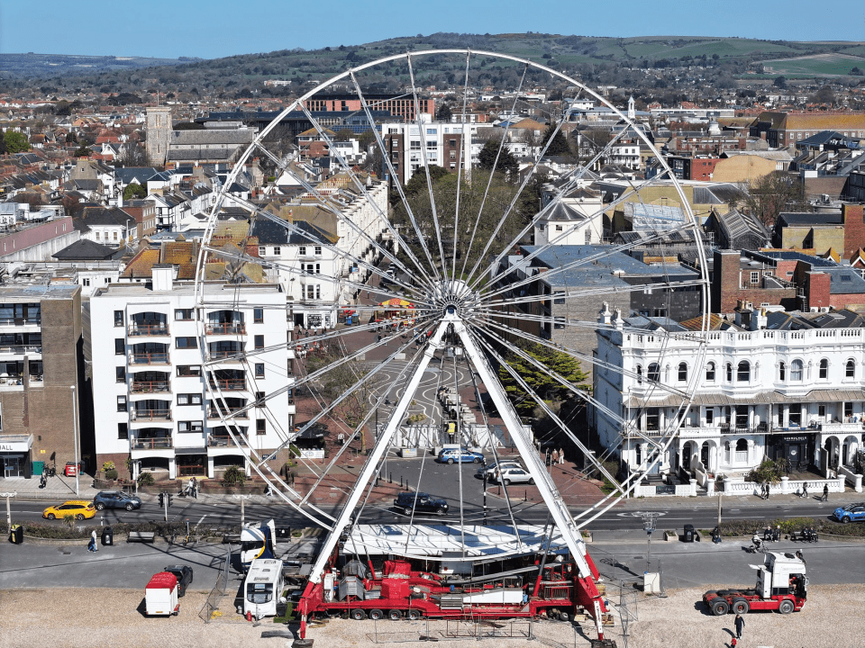 Ferris wheel being assembled in a city.