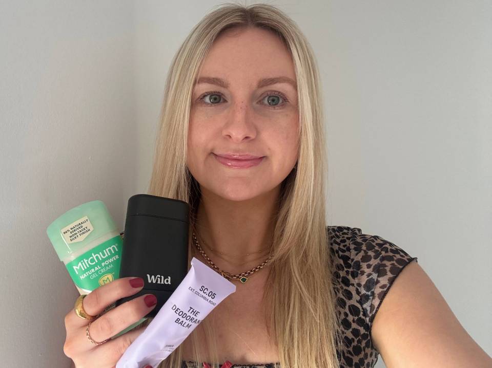 Woman holding three natural deodorants.