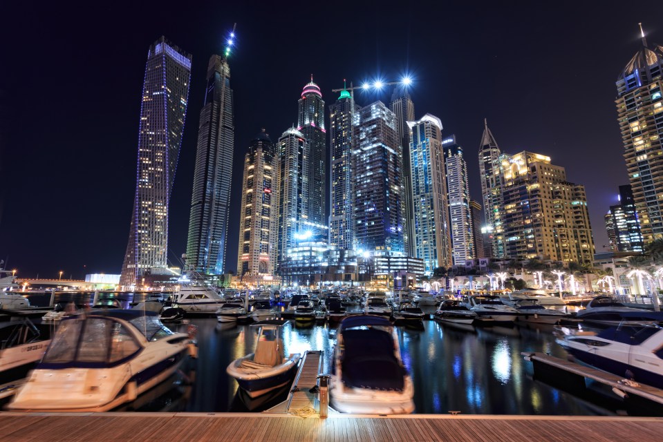 Dubai Marina at night, with skyscrapers and yachts.