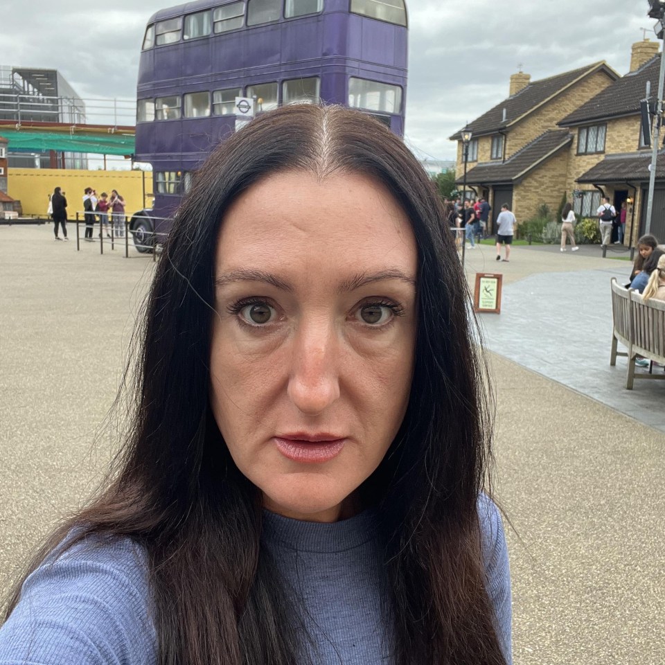 Woman with long dark hair in front of a purple bus.