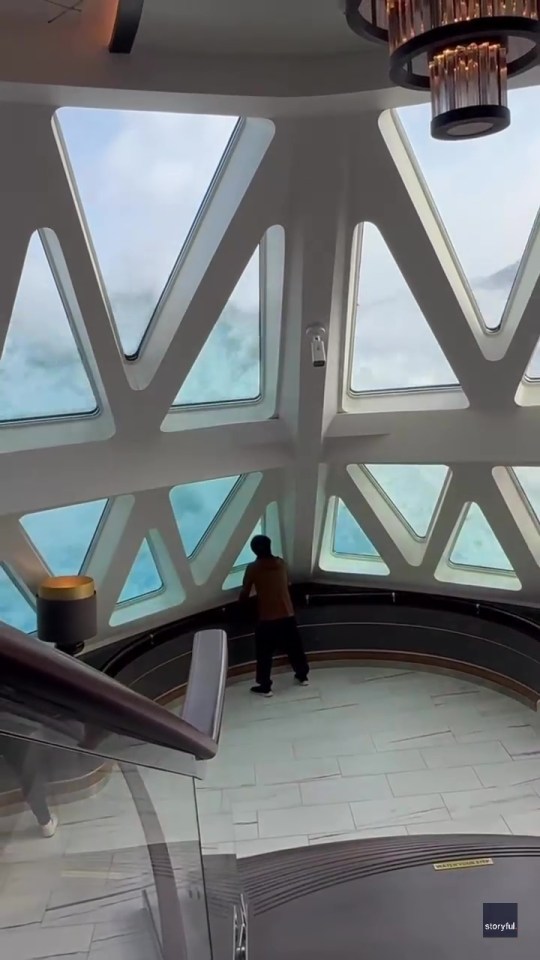 Passenger on a cruise ship looking out at large waves through a window.