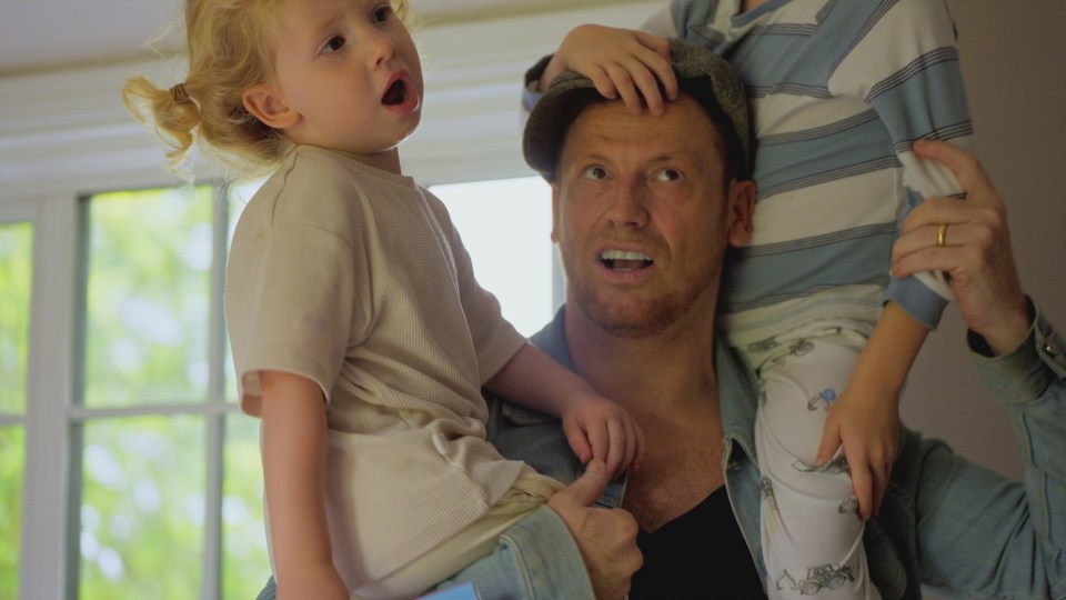 A man holding his two young children.