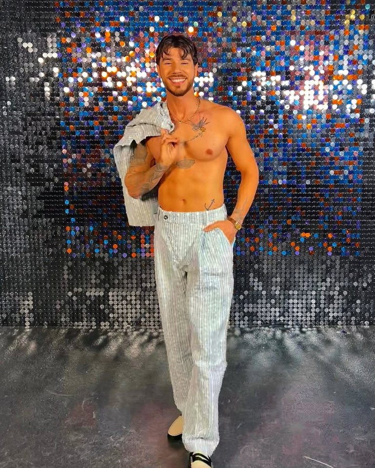 Shirtless man in striped pants posing in front of a sparkly background.