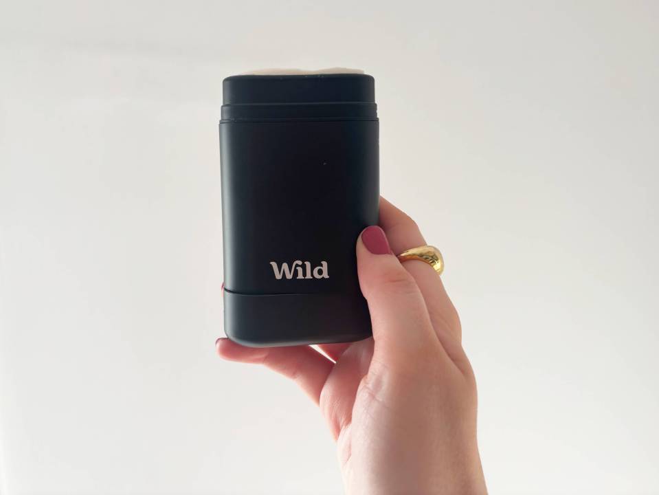 Hand holding Wild brand natural deodorant.