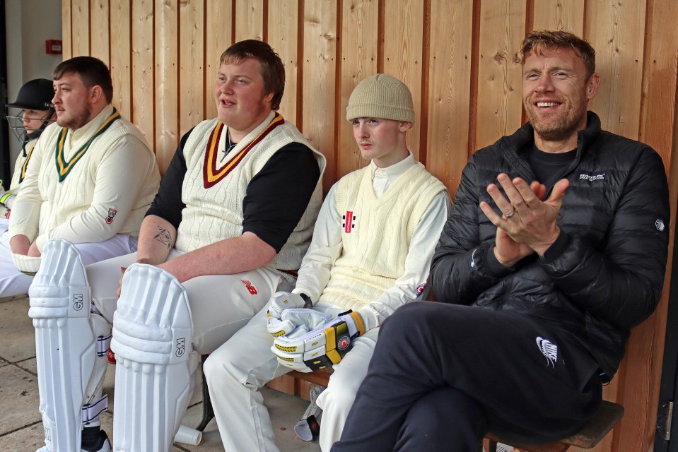 Cricket players and Freddie Flintoff sitting on a bench.