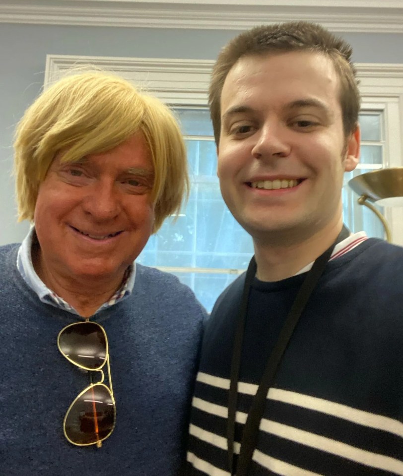 Photo of two men, one wearing a blond wig.