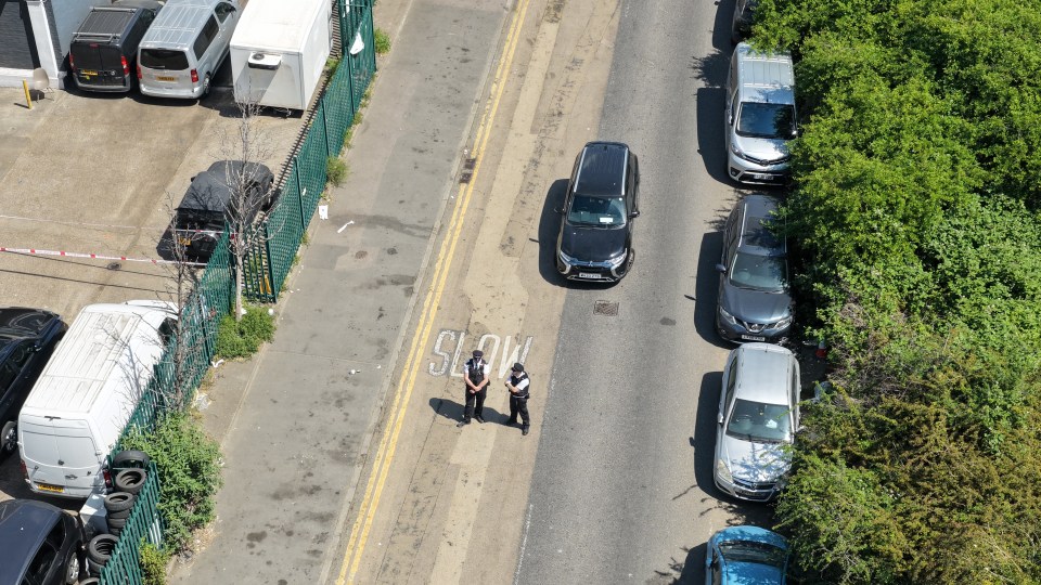 Overhead view of two police officers standing on a street next to parked cars, a crime scene.