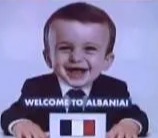 AI-generated image of a baby holding a sign that says "Welcome to Albania" displayed at a summit.