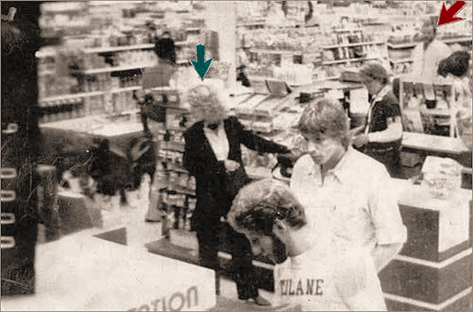 Black and white photo of a grocery store interior with several people shopping.