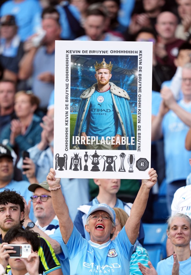 Fan holding a sign depicting Kevin De Bruyne as a king and his trophies.