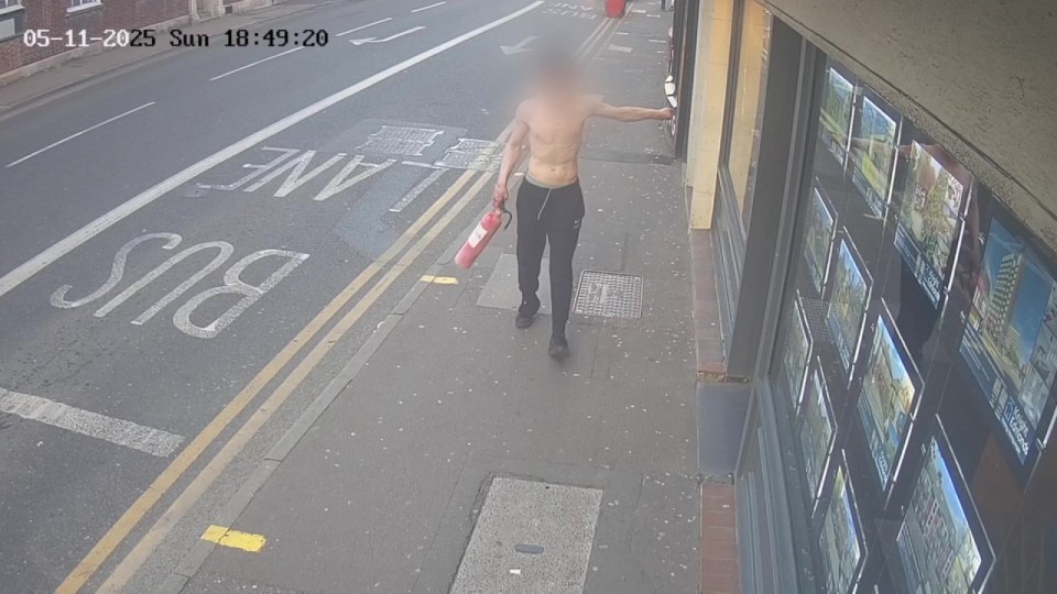Surveillance image of a shirtless man carrying a fire extinguisher.