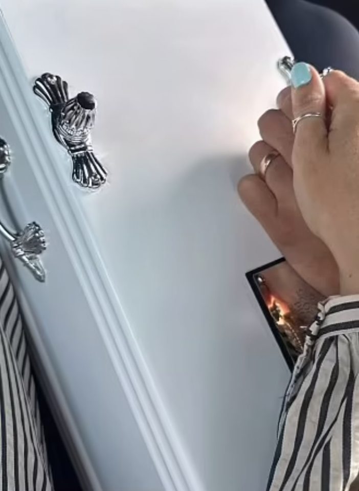 Person's hands on a white casket.