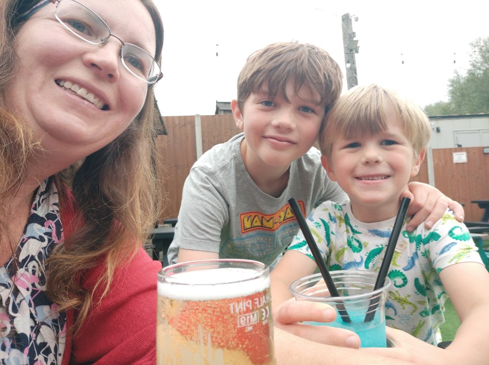 A woman and her two sons sitting outside with drinks.