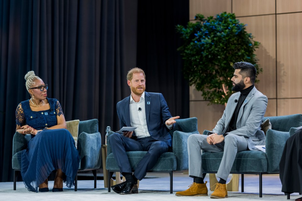 Prince Harry in conversation with two young people at a panel discussion.