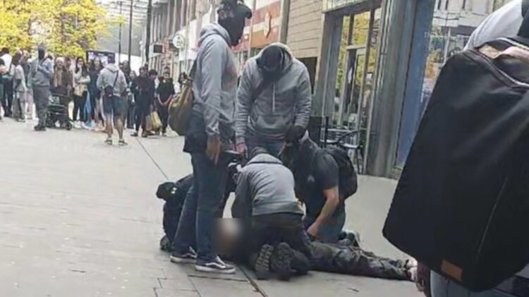 Police arresting a man on the street.