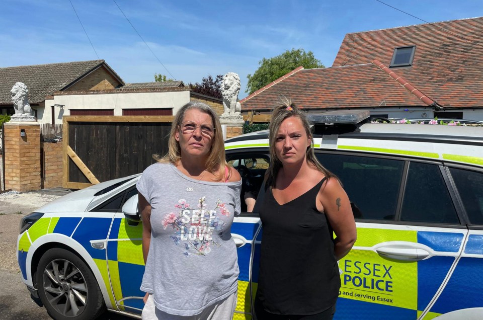 Two women stand by a police car in front of a house.
