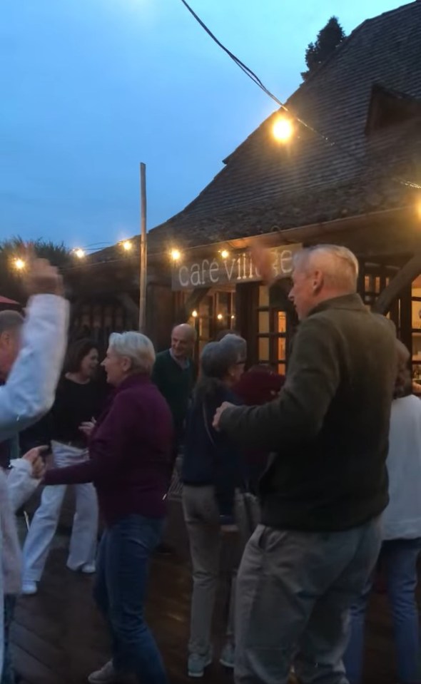 A group of people dancing outside a bar at night.