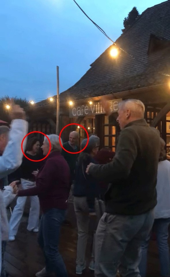 A woman dancing with a man at an outdoor cafe.