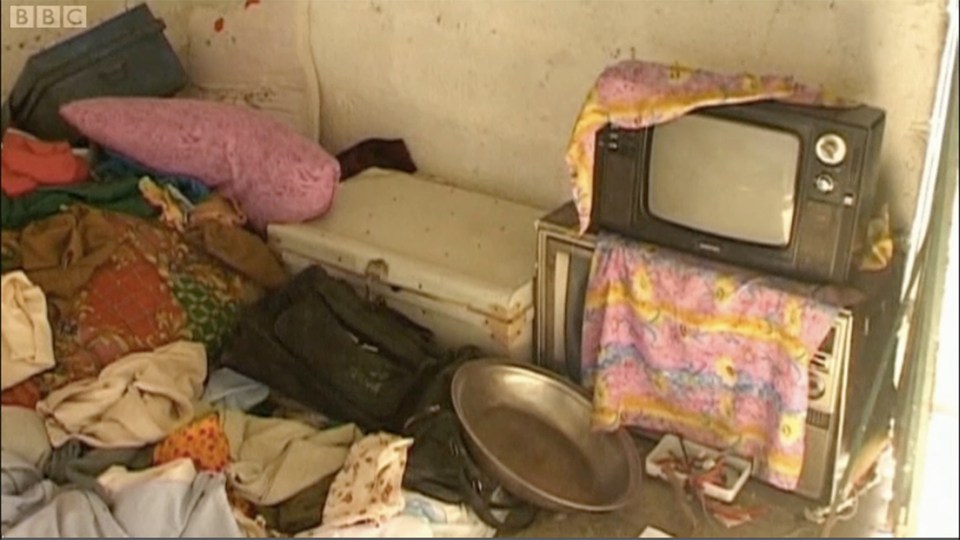 Interior of Osama bin Laden's compound in Abbottabad, Pakistan, showing a cluttered room with a television, clothes, and other belongings.