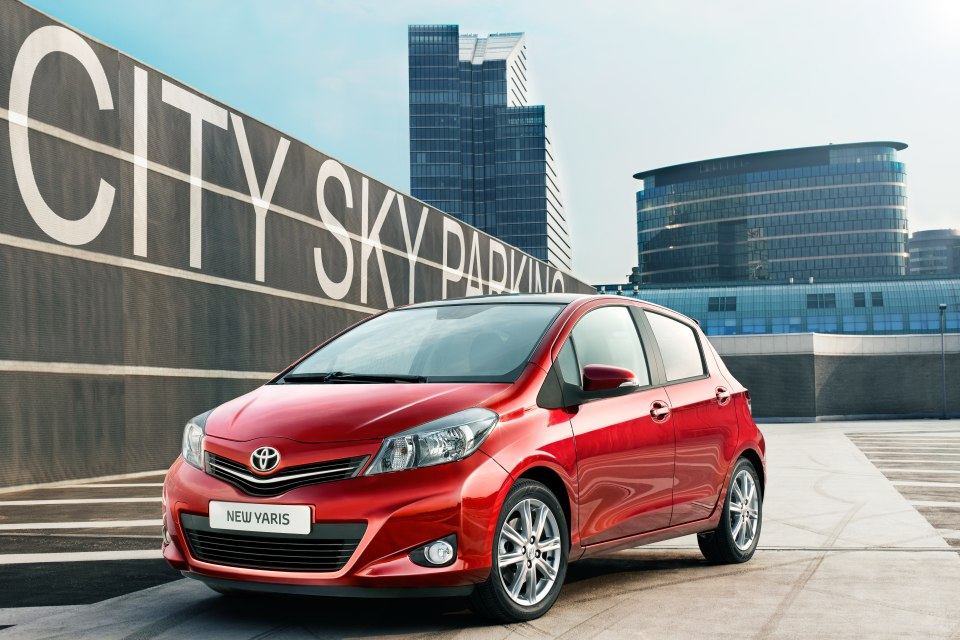 Red Toyota Yaris parked in a city parking lot.