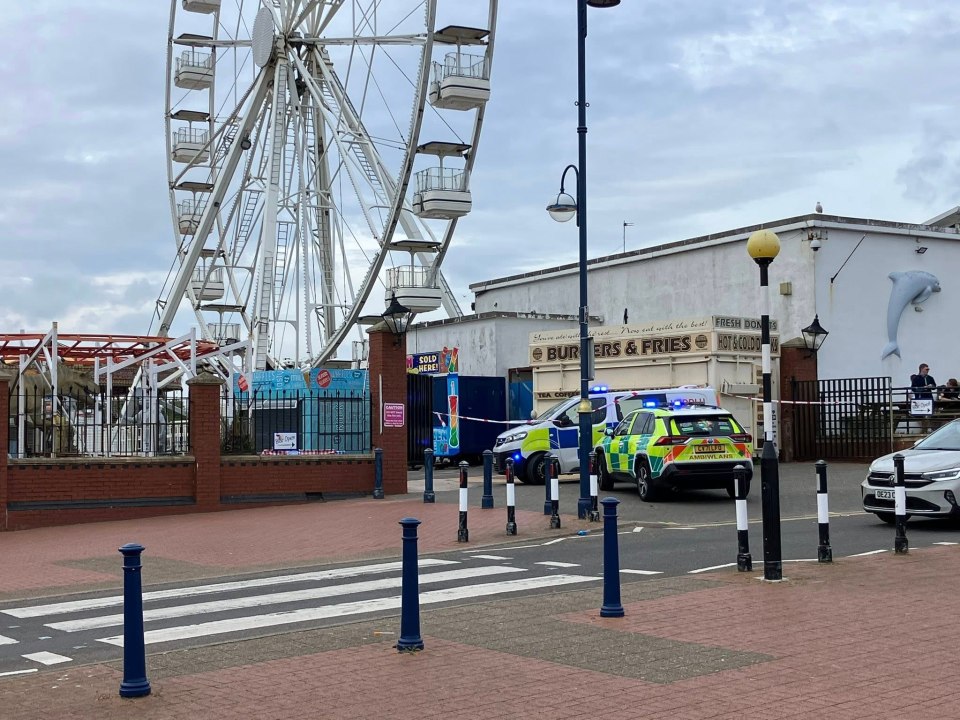Police and ambulance vehicles at a seaside pleasure park following a teenager's death.