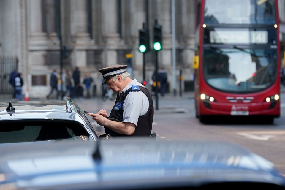 Traffic warden writing a parking ticket.