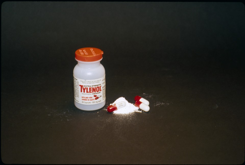 Tylenol bottle and capsules spilled on a dark surface.