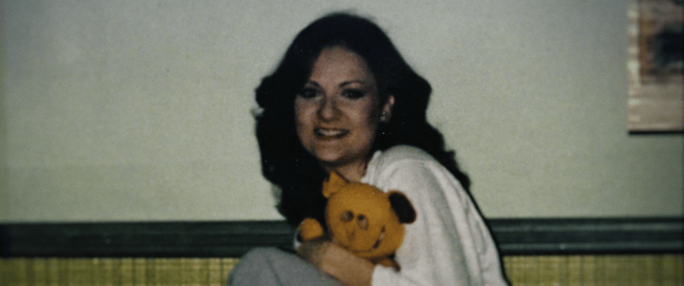 Still image of a woman holding a stuffed animal.