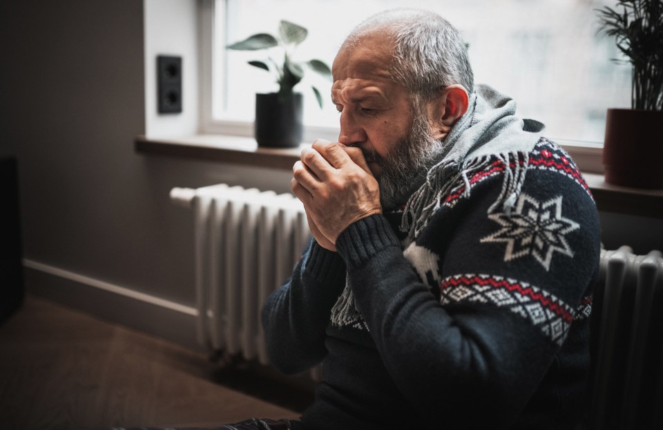 Man warming hands near radiator.