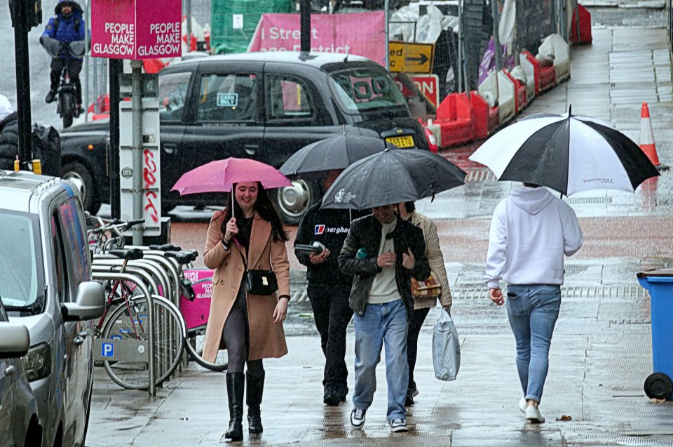 People walking in a rainy city center, using umbrellas.