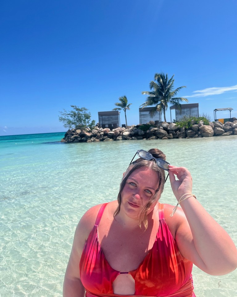 Woman in red swimsuit in shallow turquoise water.
