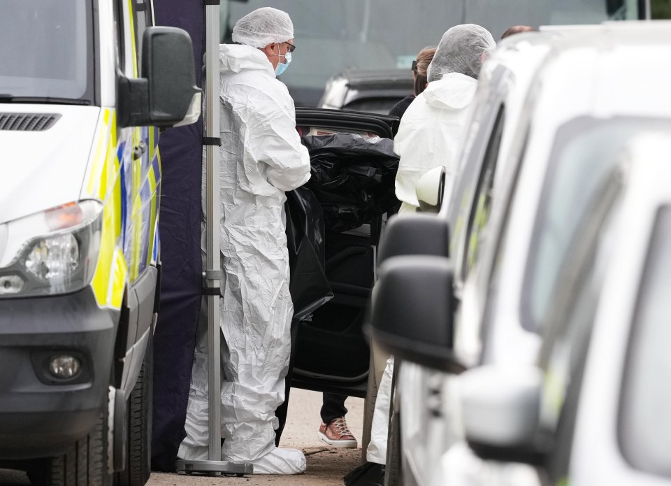 Forensic officers investigating a body found in a car.